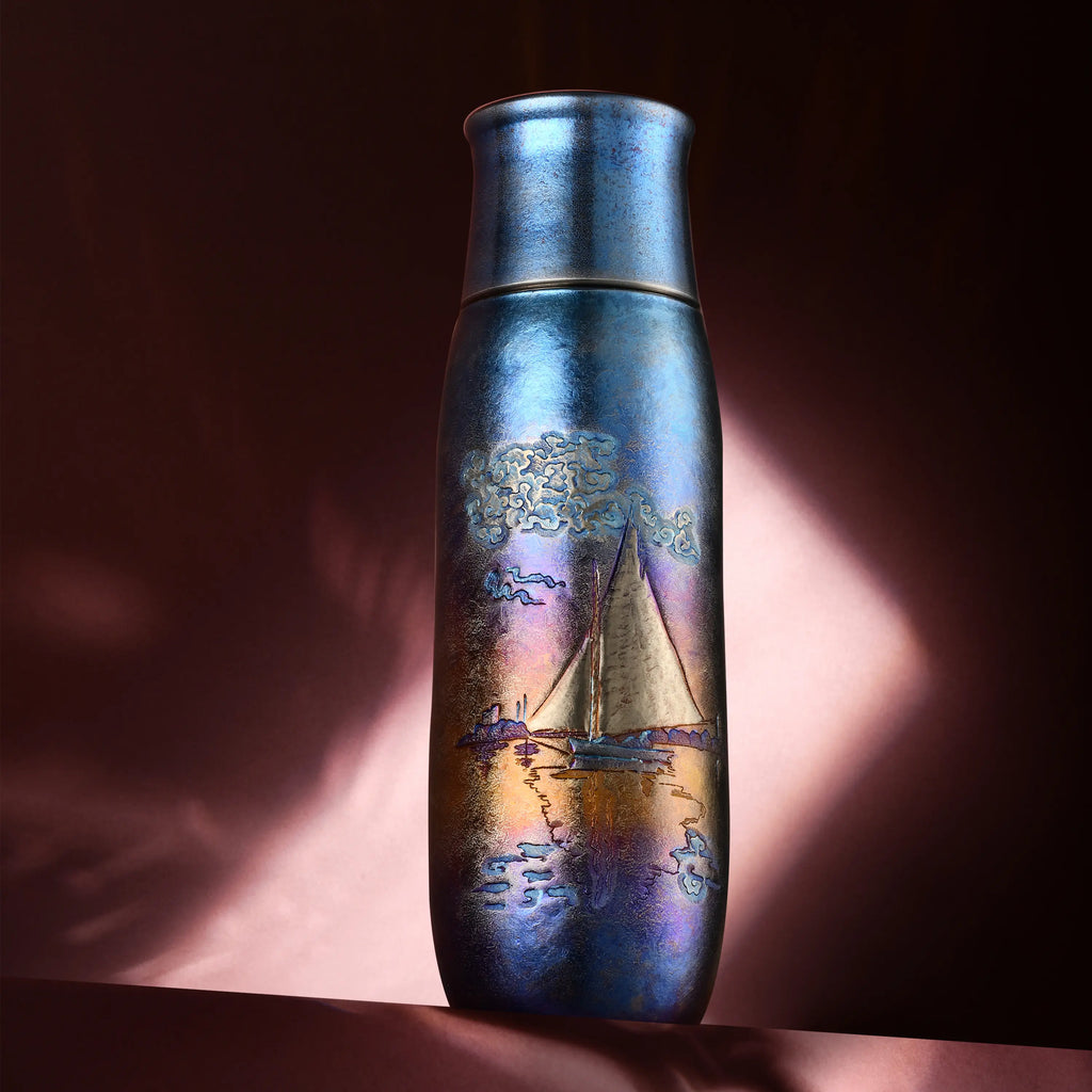 Monet Sailboat pure titanium infuser tumbler in iridescent blue on draped pink fabric under dramatic light