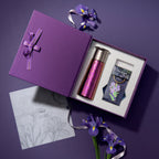 Top-down flat lay of open titanium tumbler gift box with iris charm, sketch card and fresh purple iris blooms