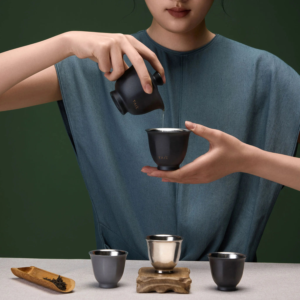Pure titanium travel tea set in use, pouring tea from black gaiwan into a cup held by hand
