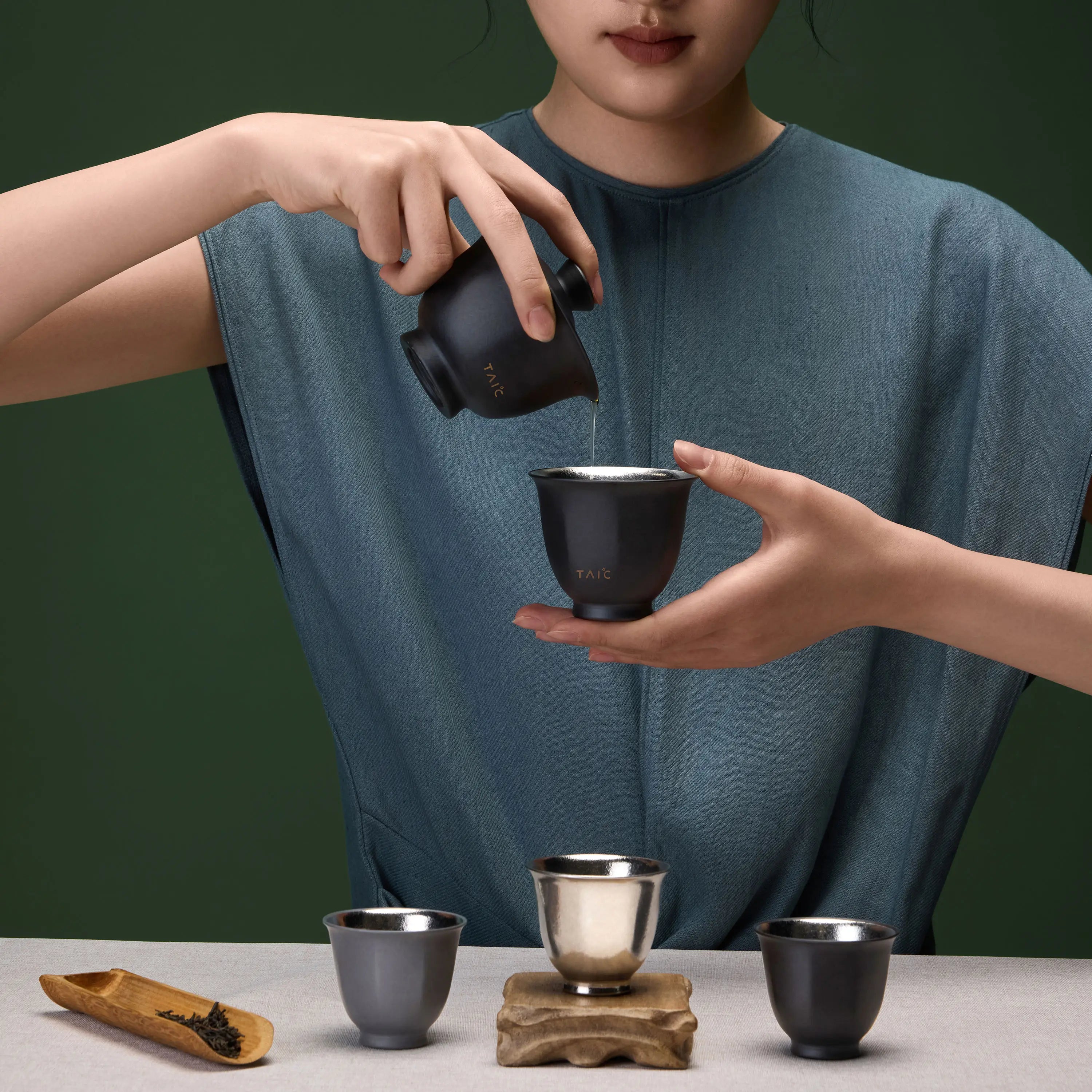 Pure titanium travel tea set in use, pouring tea from black gaiwan into a cup held by hand