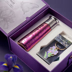 Close-up 45-degree view of titanium tumbler with iridescent purple-gold finish resting in gift box with iris enamel keyring