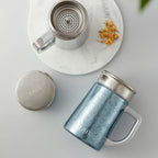 Pure titanium office mug 450mL top view with micro-mesh infuser and round lid beside jasmine flowers