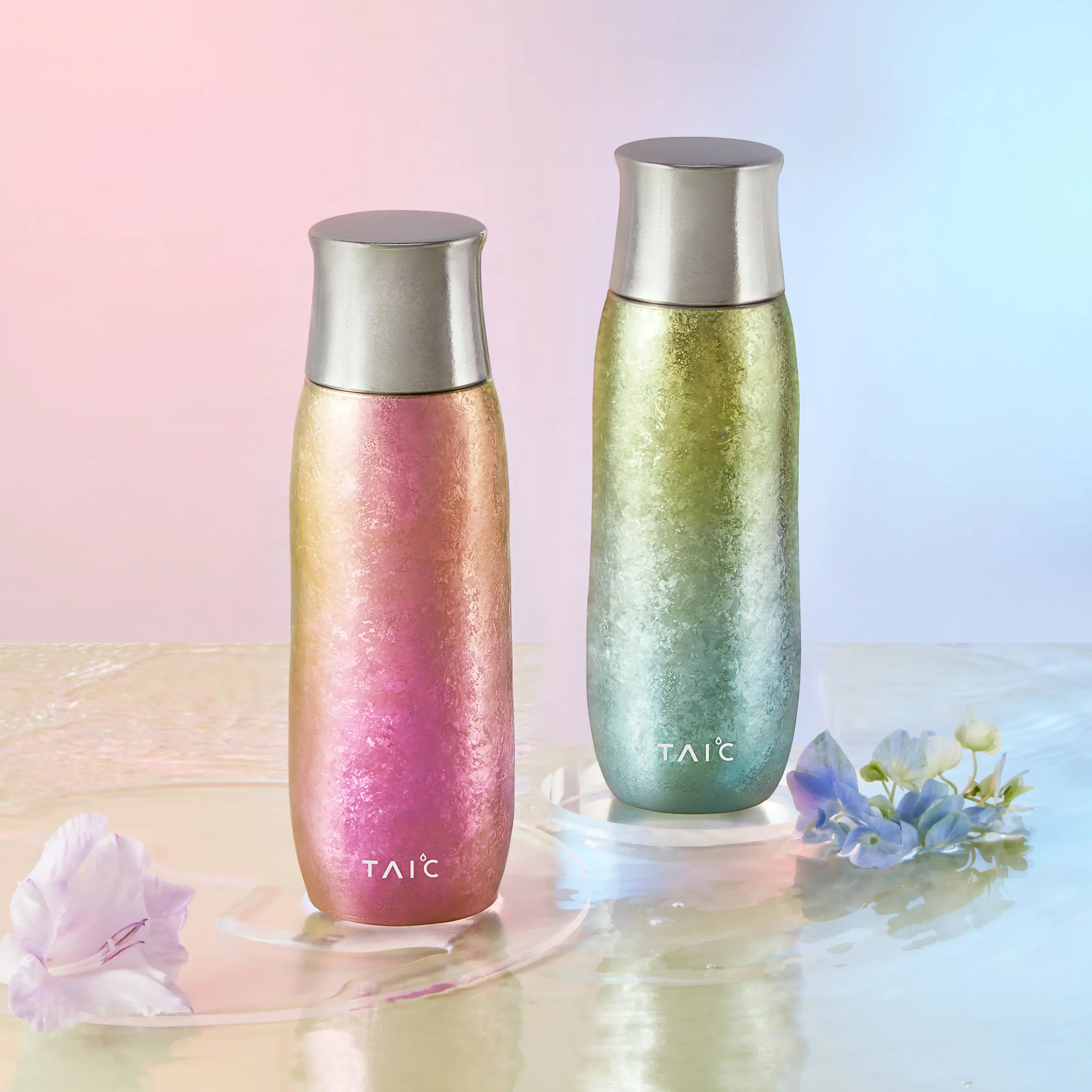 Pink and green Aurora pure titanium tea infuser tumblers on rippling water with fresh spring flowers