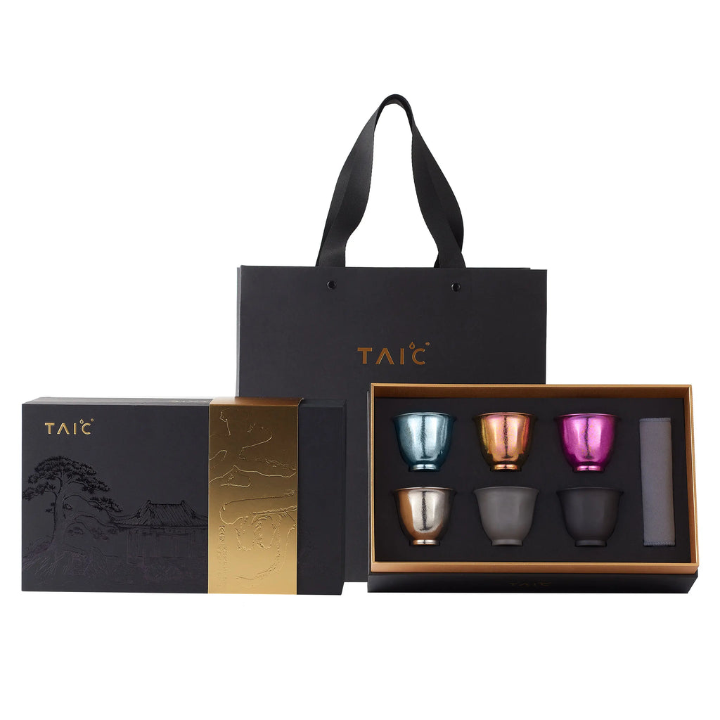 Pure titanium tea cup gift set — open box showing six colored cups in gold tray with matching gift bag on white