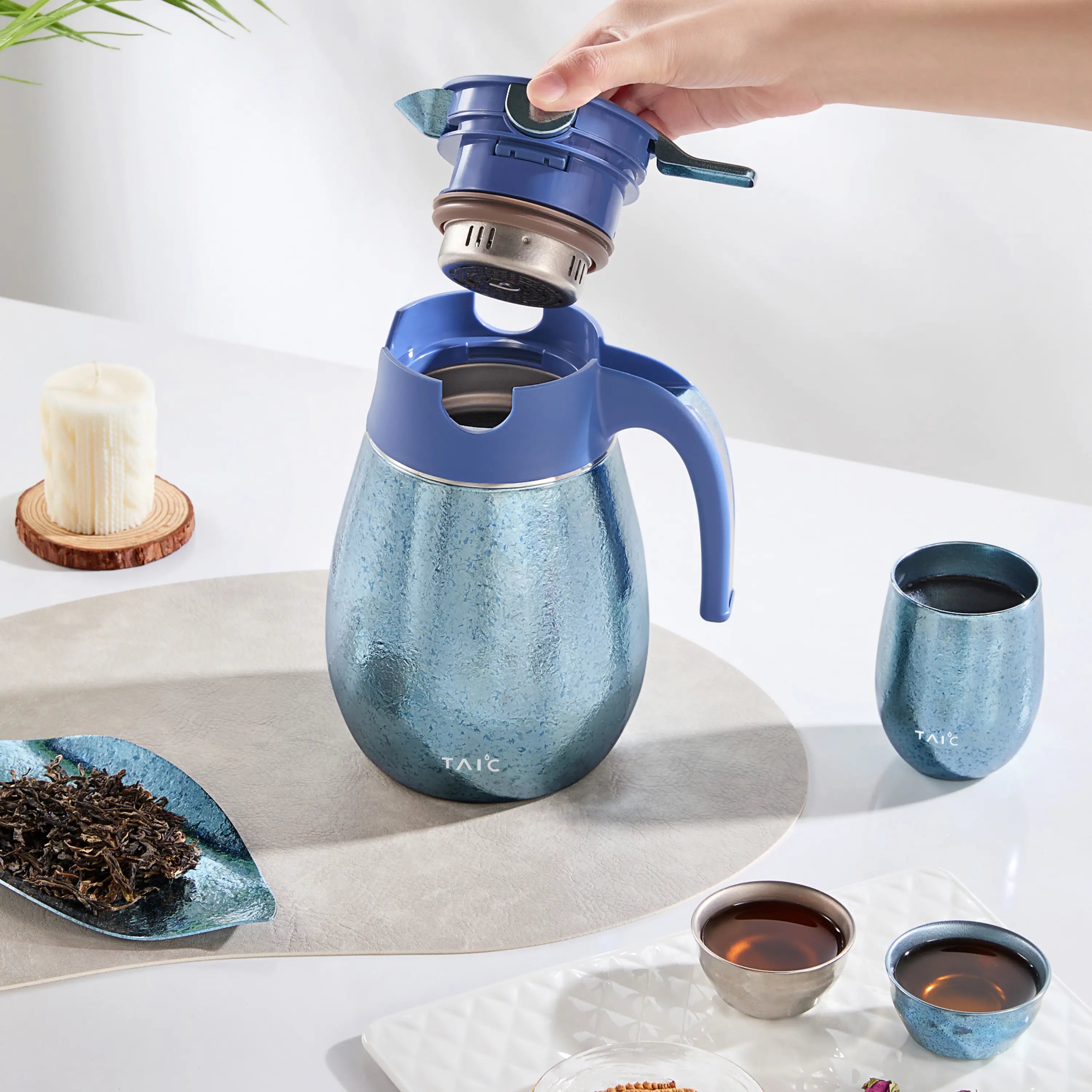 Hand lifting the dual-filter lid module from a blue titanium thermal carafe, showing the steeping basket