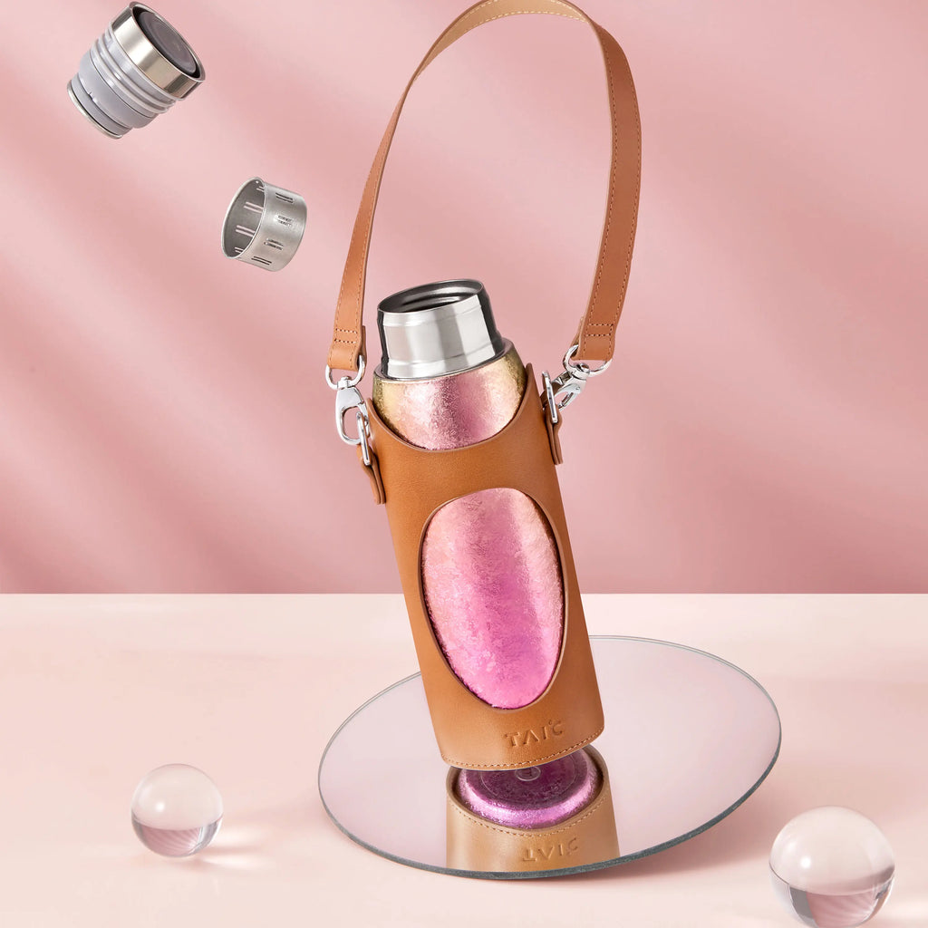 Aurora titanium tea infuser tumbler in tan leather carrier sleeve with strap, pink finish, cap parts floating above