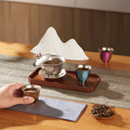 Pure titanium tea set scene, open silver gaiwan with tea leaves, colored cups and mountain rest