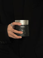 Кофейная кружка BlackInTi из чистого титана — кружка в руке на фоне тёмной одежды, виден серебристый ободок