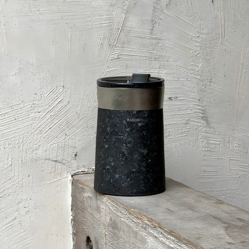 Кофейная кружка BlackInTi из чистого титана — кружка стоит на бетонном выступе у текстурированной белой стены